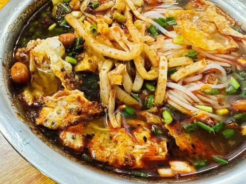 Liuzhou rice noodles (Luosifen) with spicy broth, bamboo shoots, peanuts, and herbs.