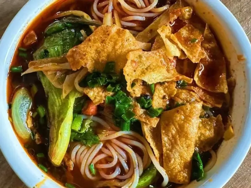 Liuzhou rice noodles (Luosifen) with spicy broth, bamboo shoots, peanuts, and herbs.